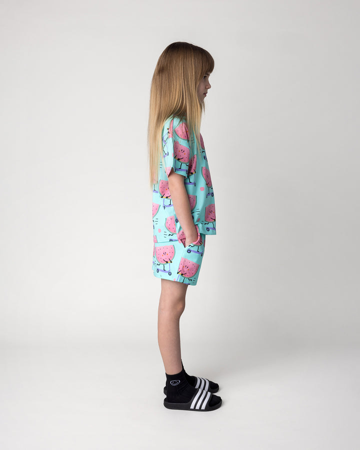 Kid wearing the Scooting Watermelon Tee in light mint with the Scooting Watermelon Short in light mint, side view