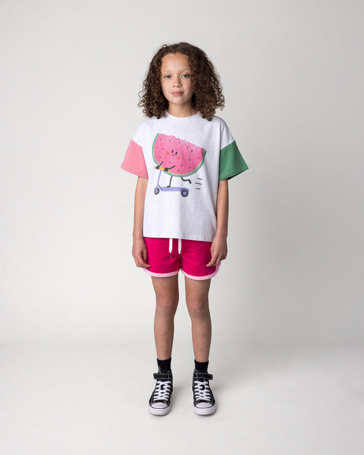 Kid wearing the Scooting Watermelon Tee in white marle, candy and green with the Sprint Short in crimson and pink, front view