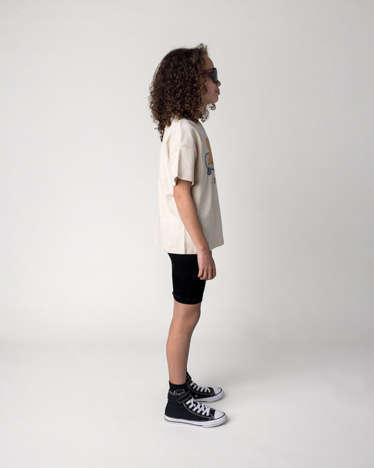 Kid wearing the Skate Puppy Tee in stone with the Velvet Bike Pant in black, side view