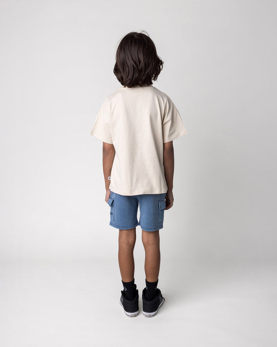 Kid wearing the Skate Puppy Tee in stone with the Blasted Deluxe Cargo Short in midnight wash, back view