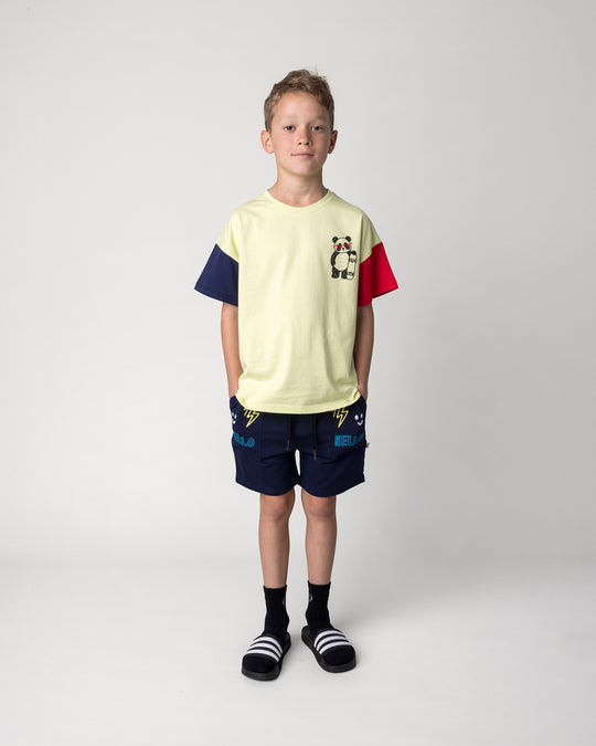 Kid wearing the Skate Panda Tee in light zest, ink and red with the Badges Short in ink, front view