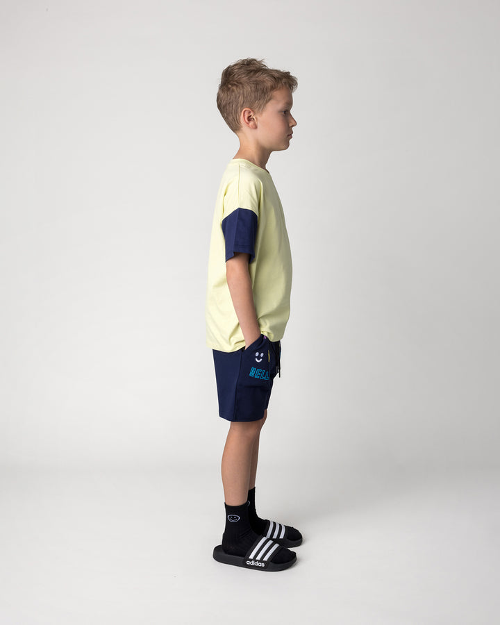 Kid wearing the Skate Panda Tee in light zest, ink and red with the Badges Short in ink, side view
