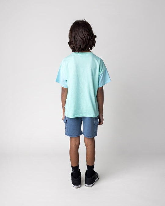 Kid wearing the Stay Cool Tee in seafoam and light aqua with the Blasted Deluxe Cargo Short in midnight wash, back view