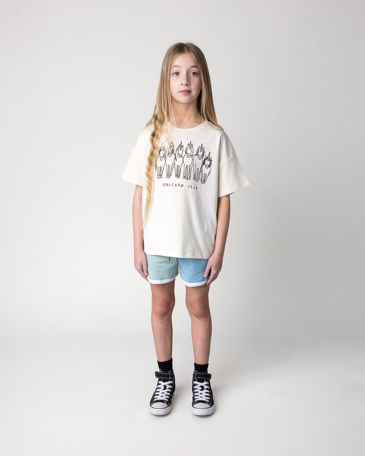 Kid wearing the Unicorn Club Tee in cream with the Sprint Short in mint, aqua and lilac, front view