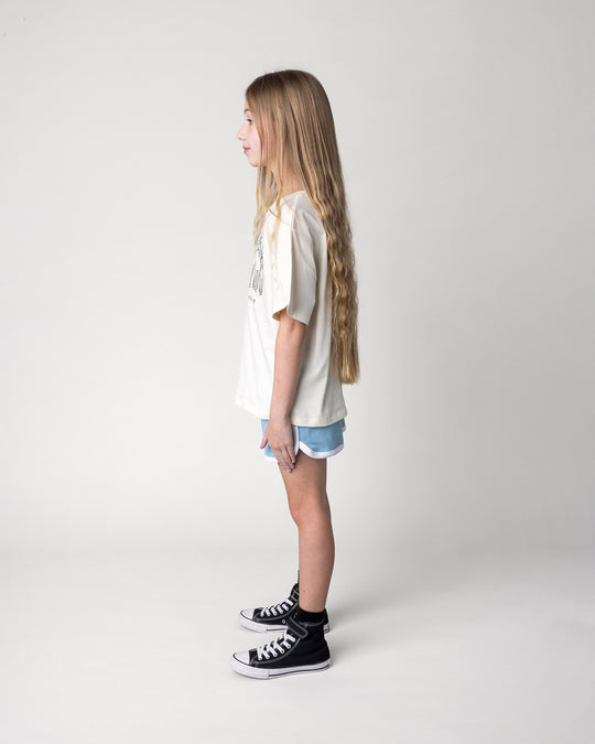Kid wearing the Unicorn Club Tee in cream with the Sprint Short in mint, aqua and lilac, side view