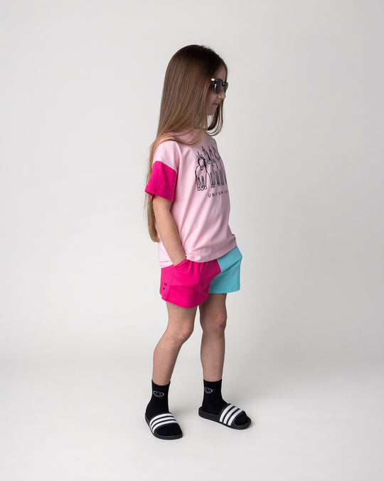 Kid wearing the Unicorn Club Tee in pink, hot pink and aqua with the Two Tone Short in hot pink and aqua, side view