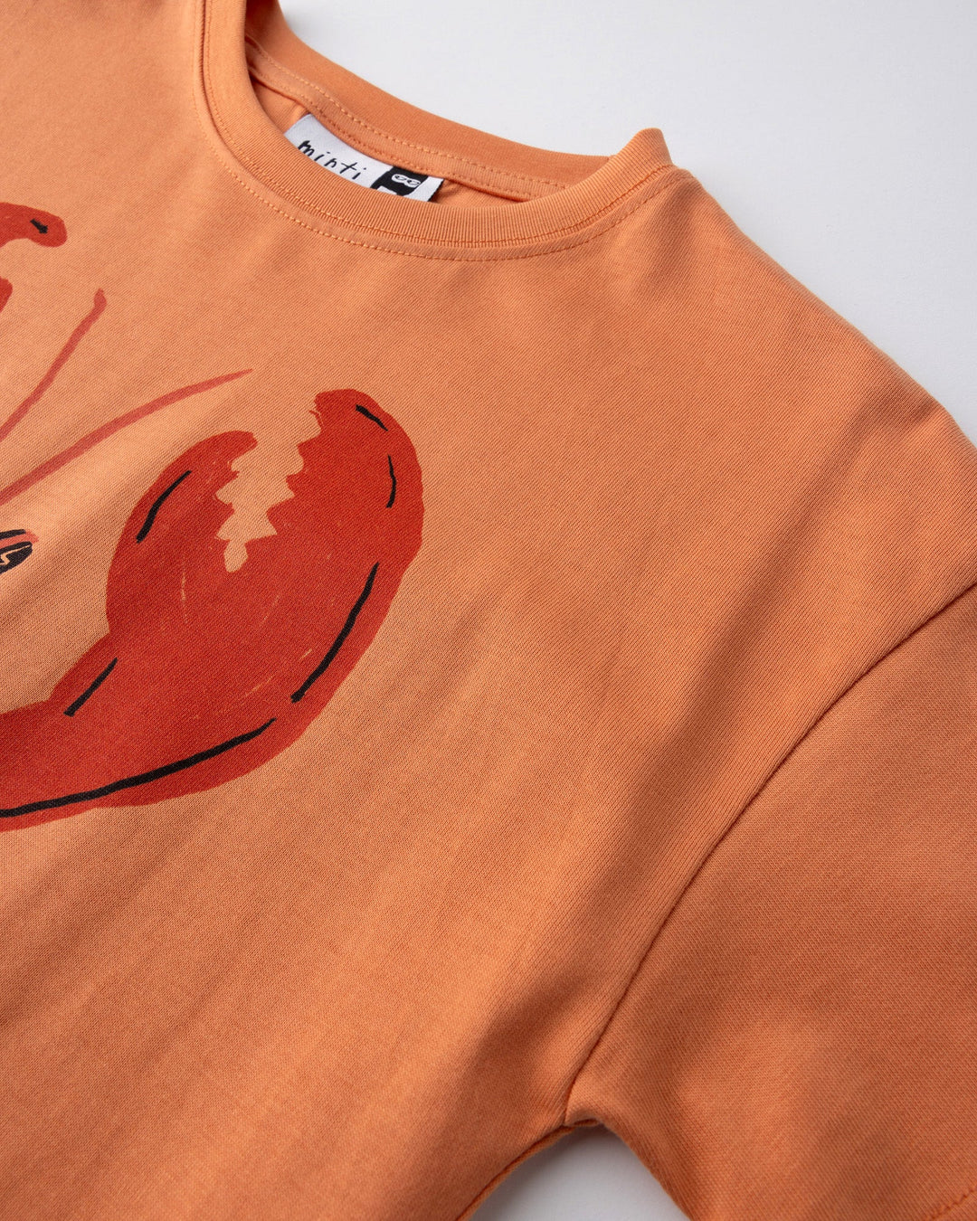Close up detail of the Vacay Crayfish Tee in light orange