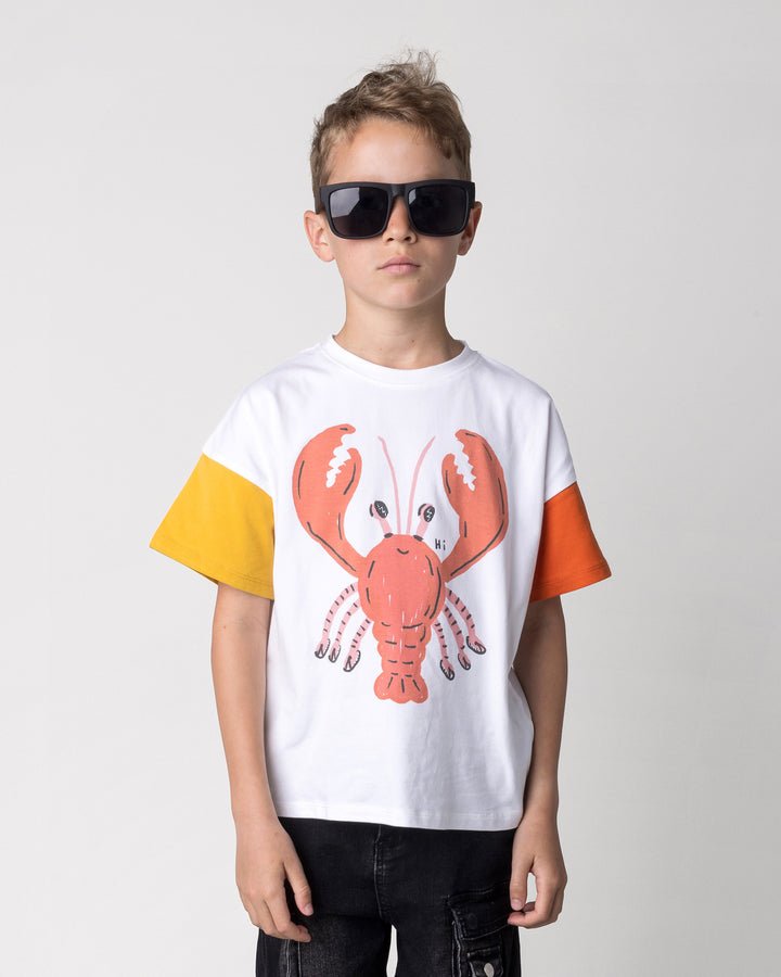 Close up of the Vacay Crayfish Tee in off white, mustard and orange on a kid, front view