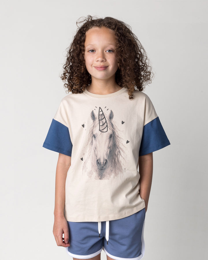Close up of the Watercolour Unicorn Tee in stone and midnight on a kid, front view