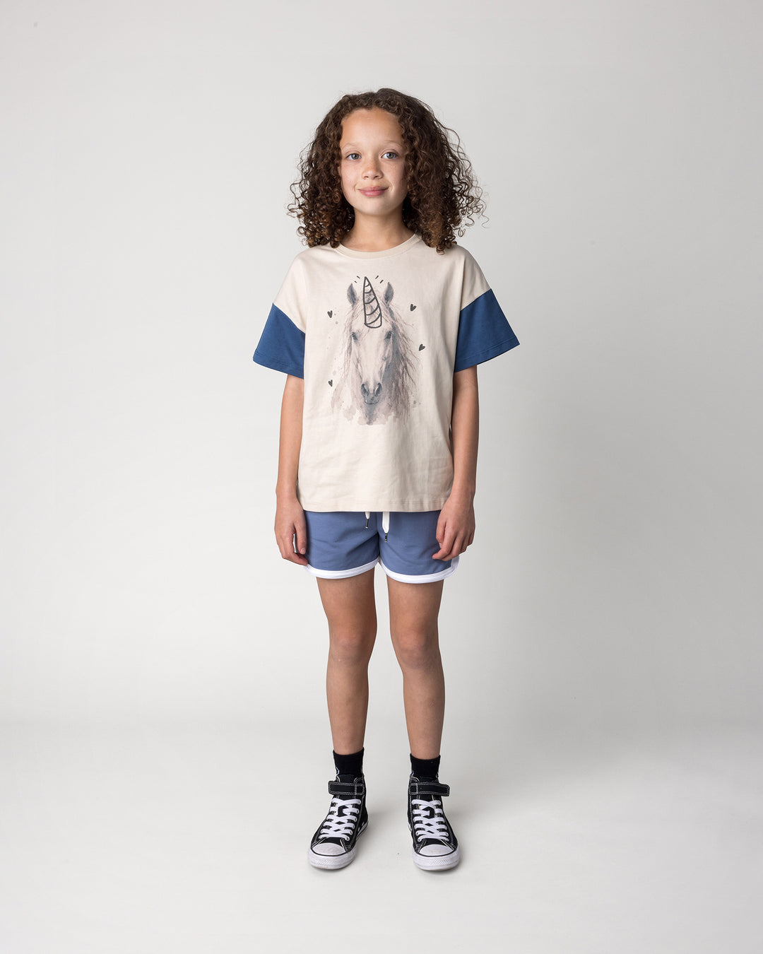 Kid wearing the Watercolour Unicorn Tee in stone and midnight with the Sprint Short in cornflower and white, front view