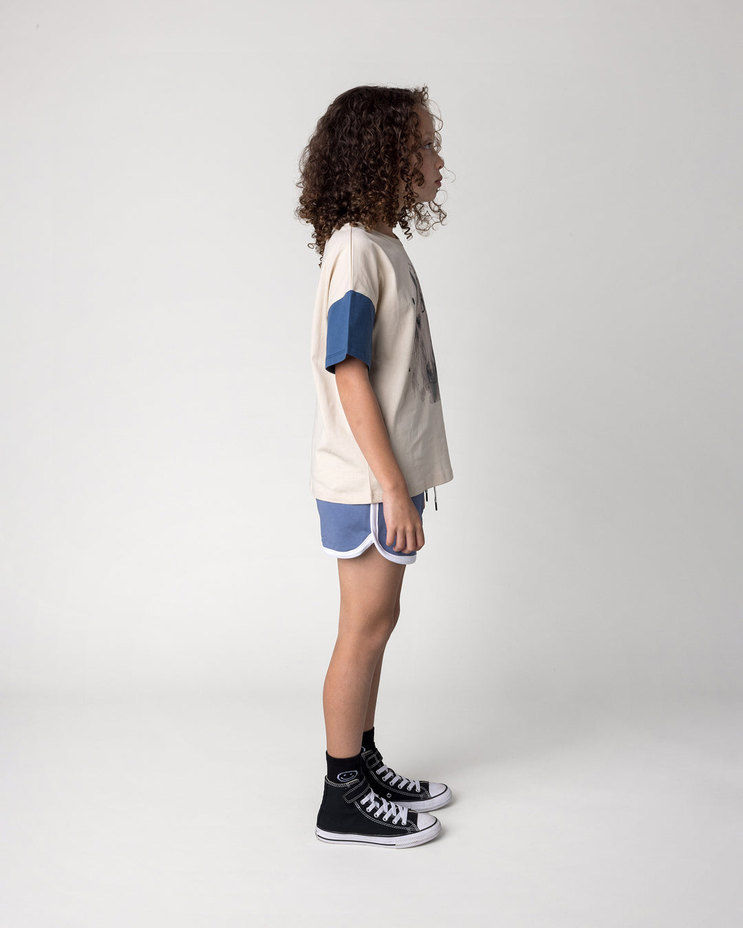 Kid wearing the Watercolour Unicorn Tee in stone and midnight with the Sprint Short in cornflower and white, side view