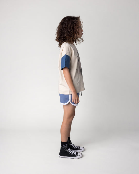 Kid wearing the Watercolour Unicorn Tee in stone and midnight with the Sprint Short in cornflower and white, side view