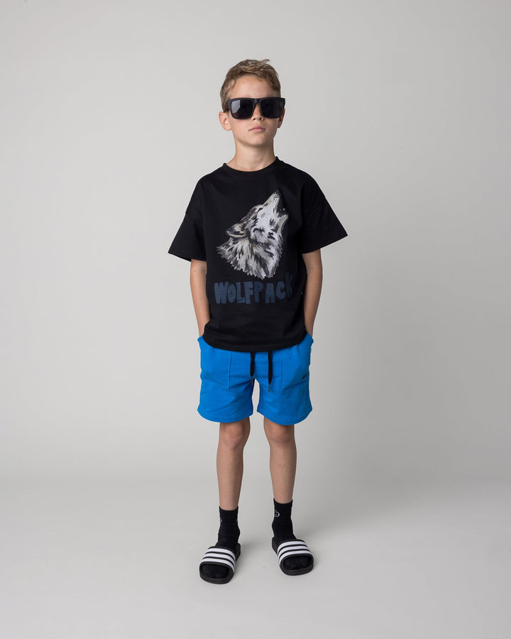 Kid wearing the Track Short in cobalt with the Fast Panda Tee in white and orange, front view