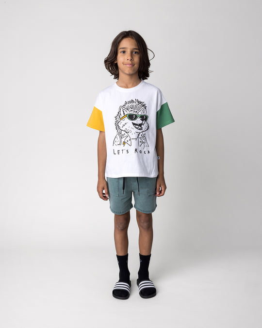 Kid wearing the Werewolf Rockstar Tee in off white, mustard and turf with the Blasted Track Short in forest wash, front view