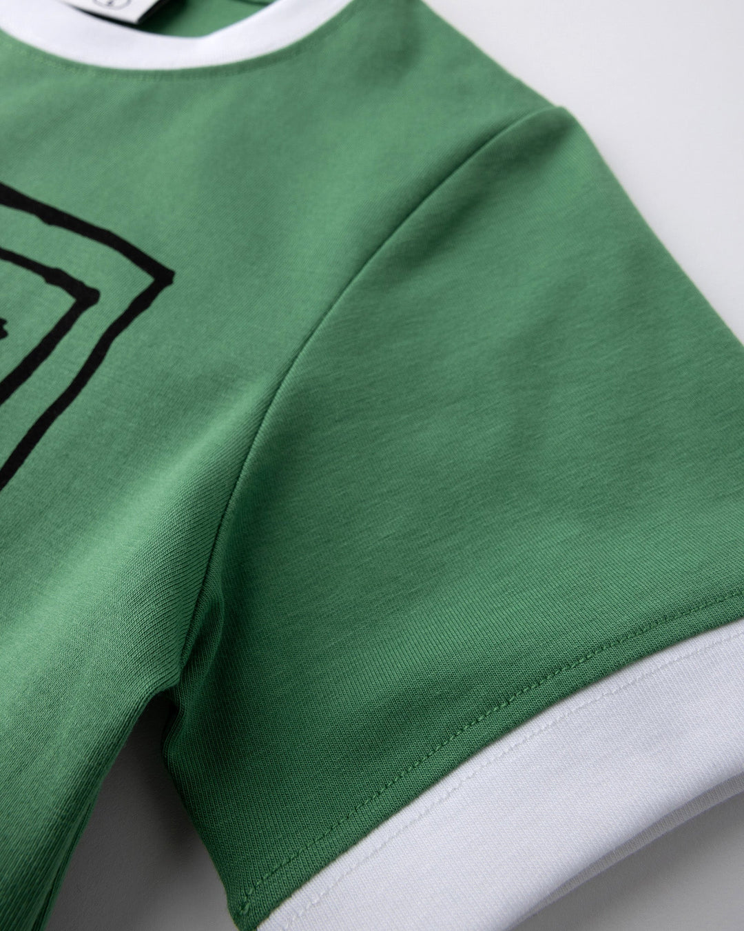 Close up detail of the Hidden Panda Tee in turf and white