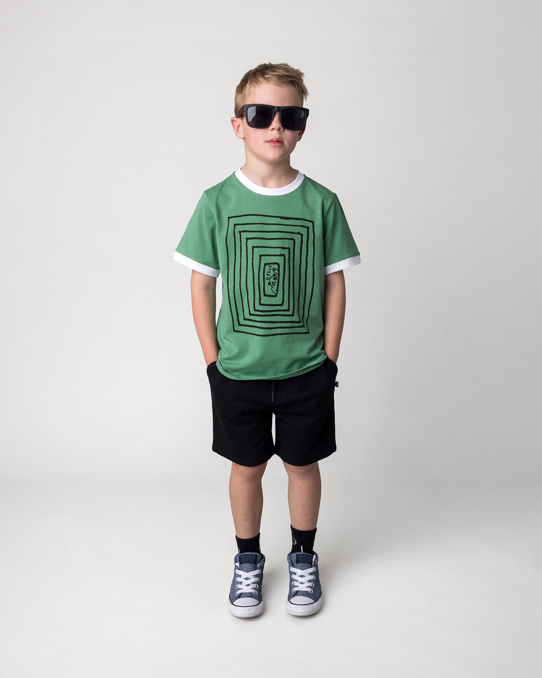 Kid wearing the Hidden Panda Tee in turf and white with the Hero Short in black, front view