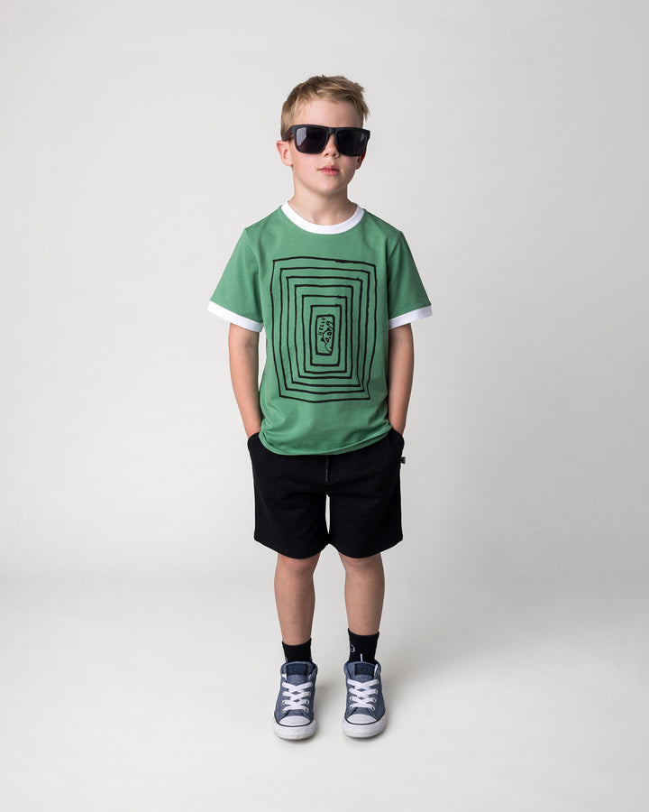 Kid wearing the Hidden Panda Tee in turf and white with the Hero Short in black, front view