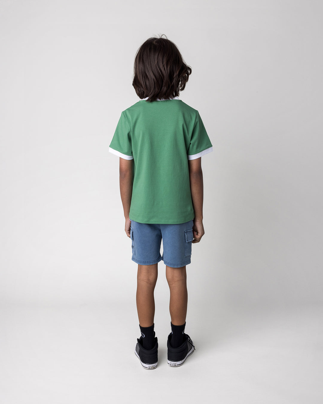 Kid wearing the Hidden Panda Tee in turf and white with the Blasted Deluxe Cargo Short in midnight wash, back view