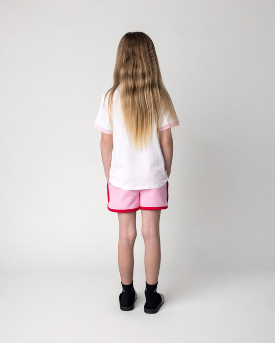 Kid wearing the Watercolour Unicorn Tee in white and pink with the Sprint Short in pink and red, back view