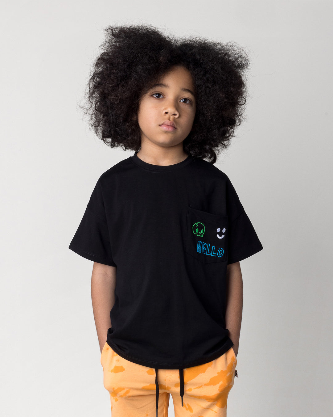 Close up of the Badges Tee in black on a kid, front view