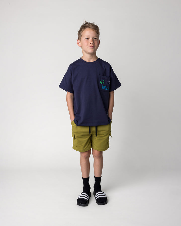 Kid wearing the Badges Tee in ink with the Deluxe Cargo Short in olive, front view