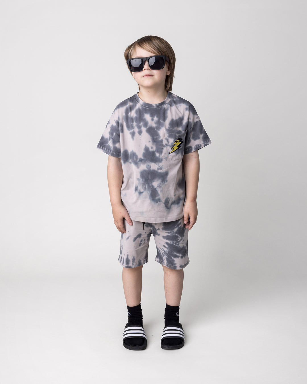 Kid wearing the Splatter Tee in grey with the Splatter Short in grey, front view