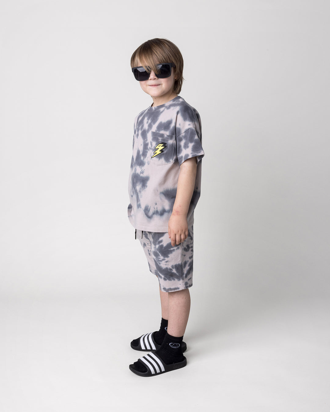 Kid wearing the Splatter Tee in grey with the Splatter Short in grey, side view