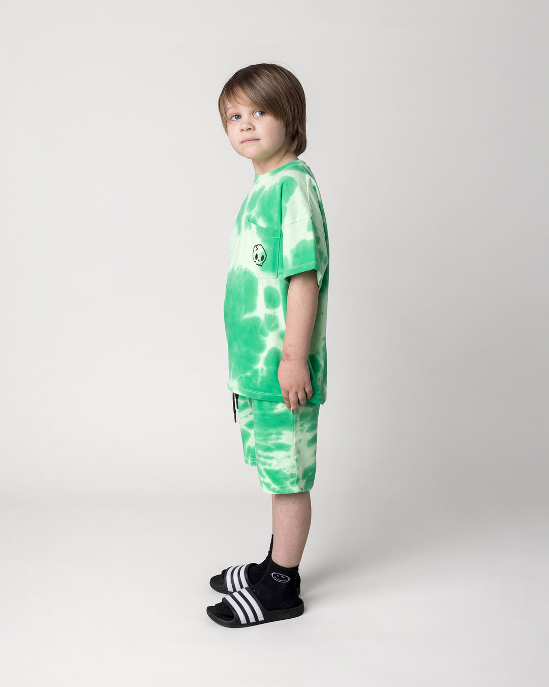 Kid wearing the Splatter Tee in green with the Splatter Short in green, side view
