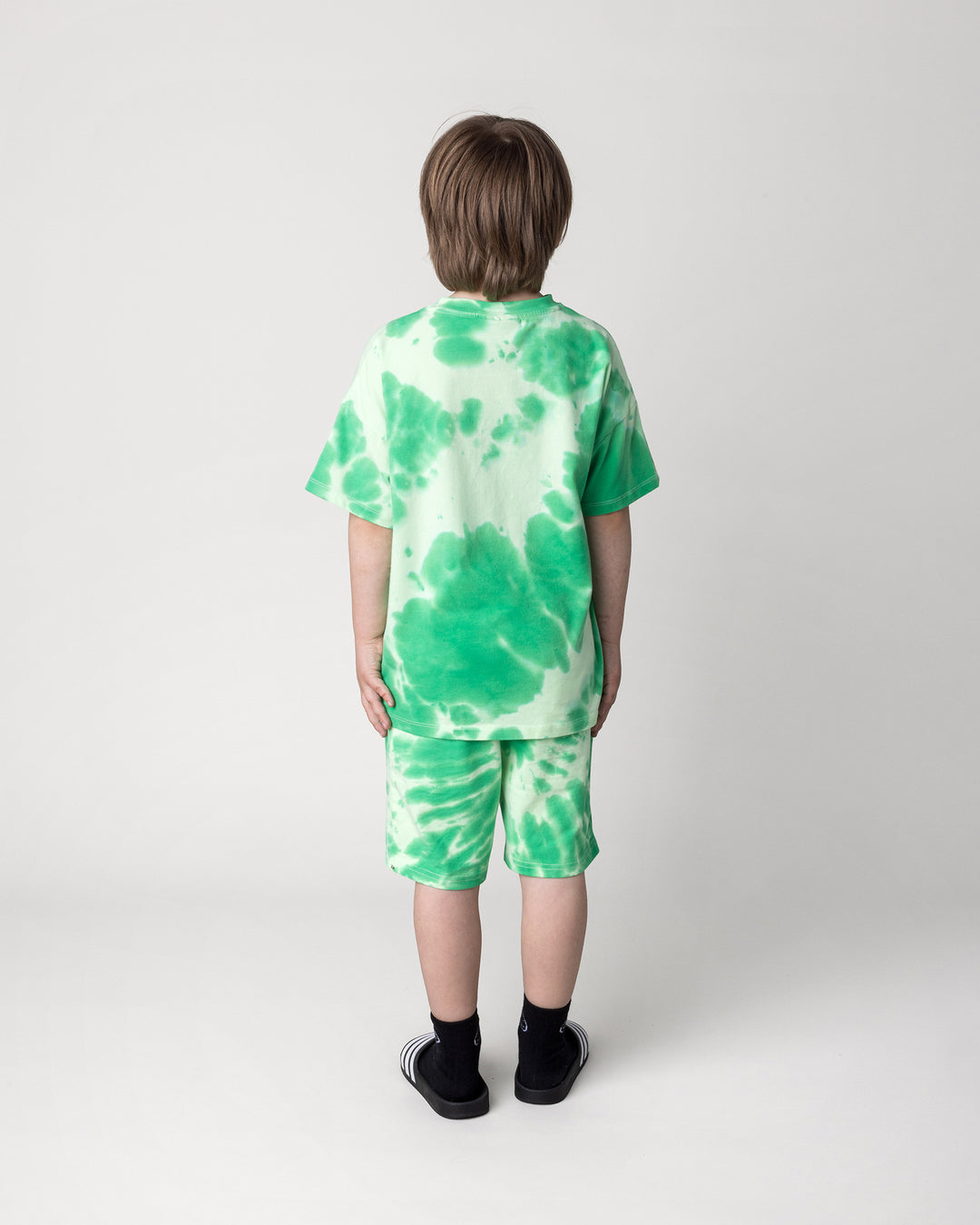 Kid wearing the Splatter Tee in green with the Splatter Short in green, back view