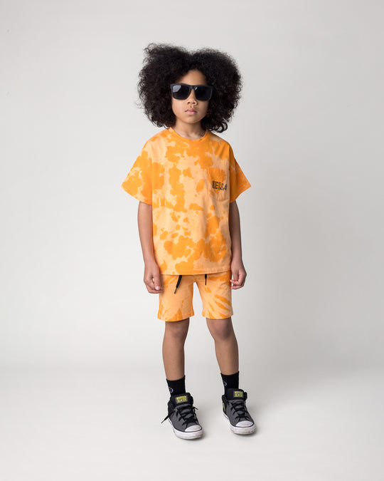 Kid wearing the Splatter Tee in orange with the Splatter Short in orange, front view