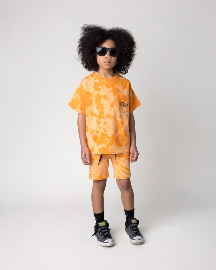 Kid wearing the Splatter Tee in orange with the Splatter Short in orange, front view