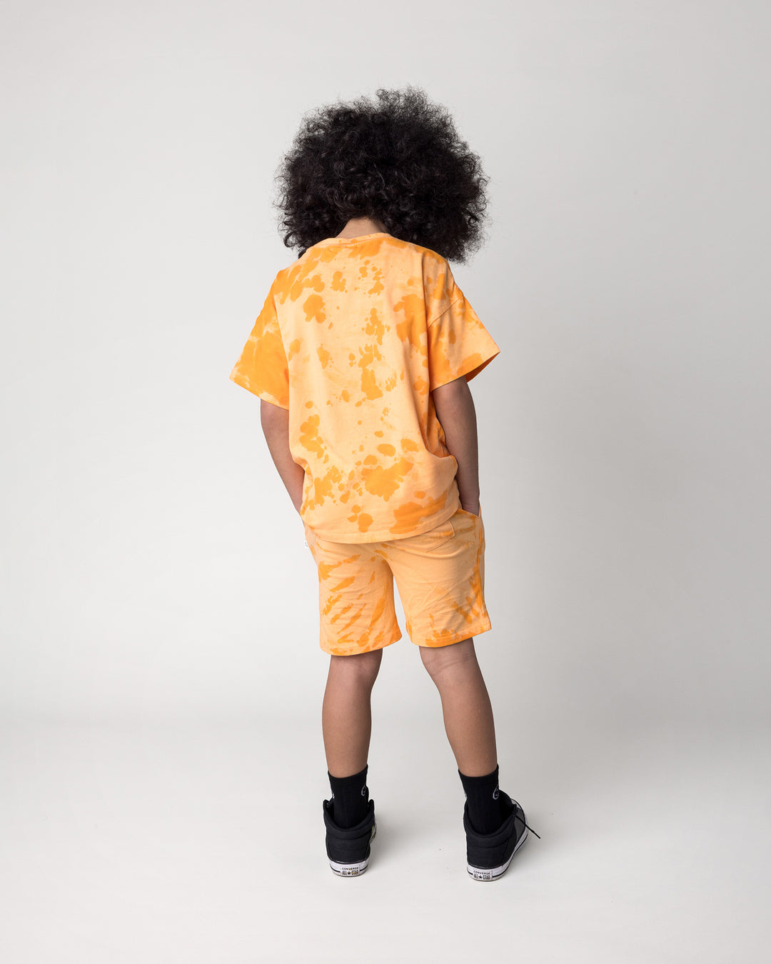 Kid wearing the Splatter Tee in orange with the Splatter Short in orange, back view