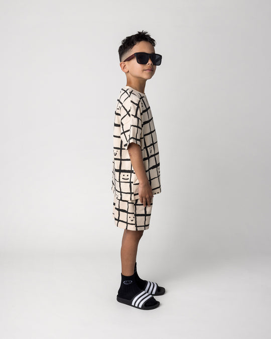 Kid wearing the Happy Squares Short in beige with the Happy Squares Tee in beige, side view