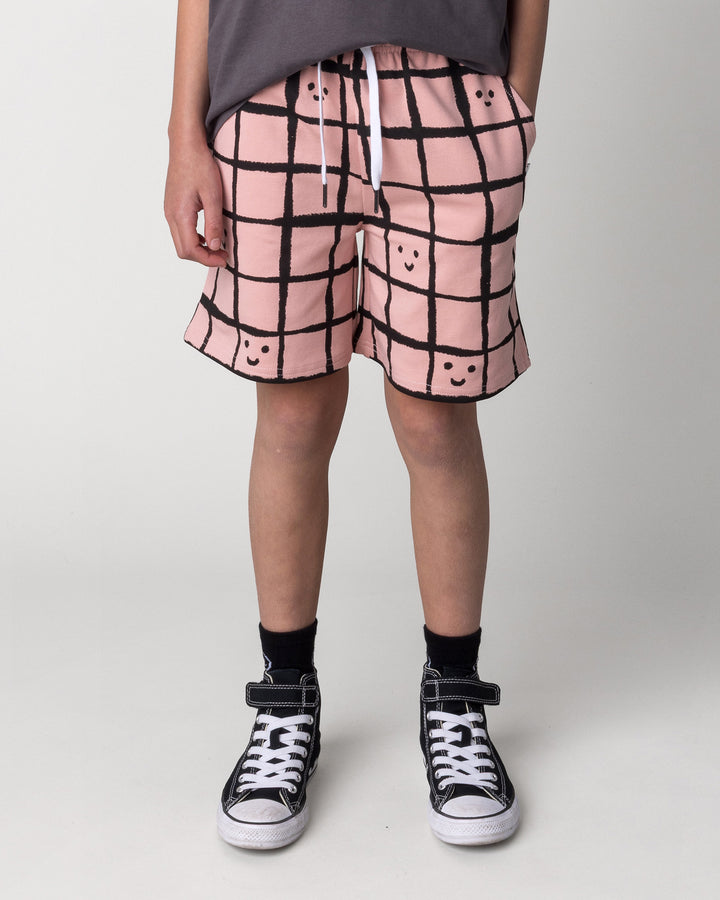 Kid wearing the Happy Squares Short in dusty pink, front view close up
