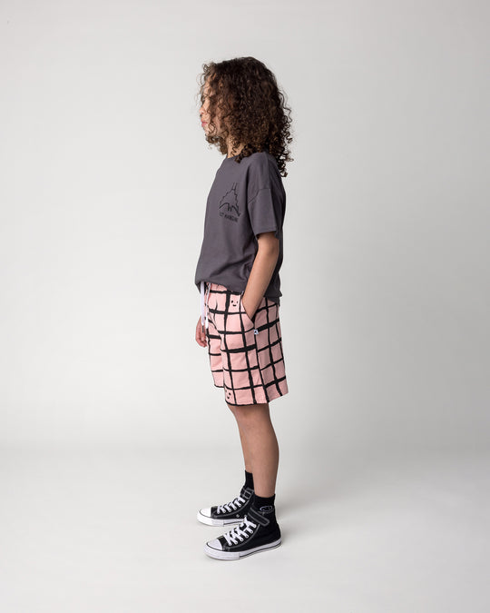 Kid wearing the Happy Squares Short in dusty pink with the Just Hanging Tee in dark grey, side view