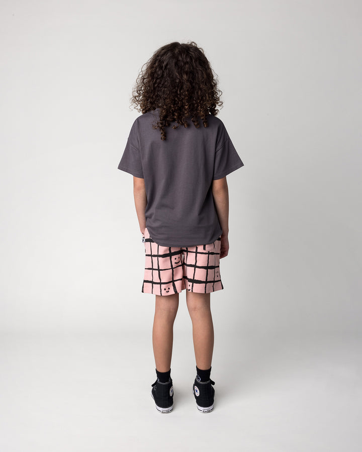 Kid wearing the Happy Squares Short in dusty pink with the Just Hanging Tee in dark grey, back view