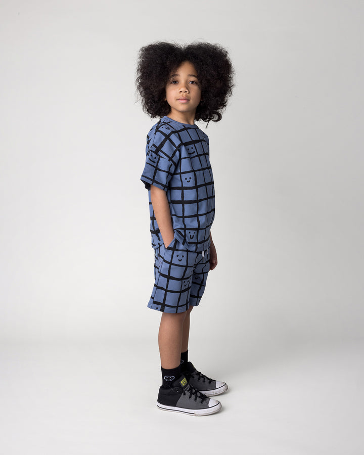 Kid wearing the Happy Squares Short in muted blue with the Happy Squares Tee in muted blue, side view