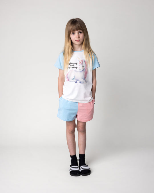 Kid wearing the Daydreaming Unicorn Tee in white and light blue with the Two Tone Short in light blue and pink, front view