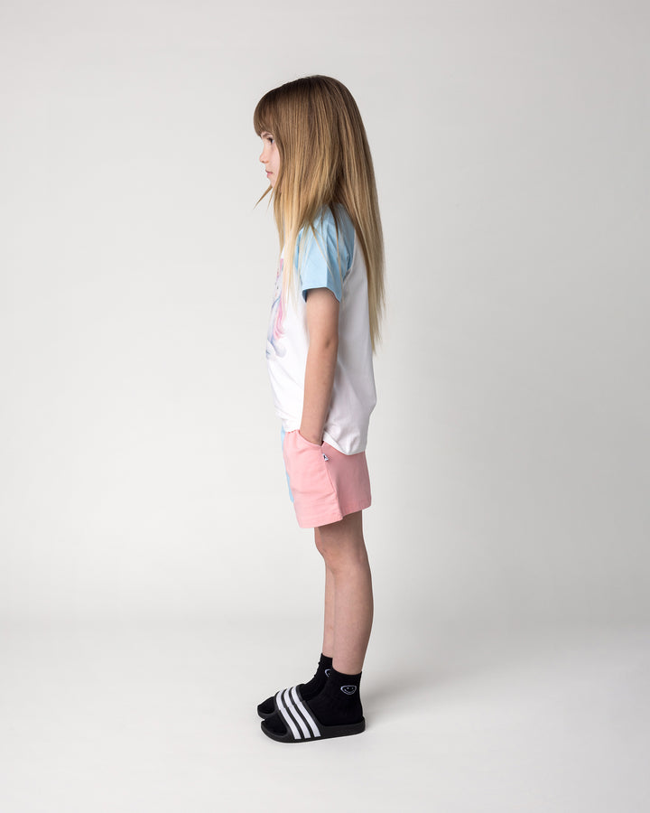 Kid wearing the Daydreaming Unicorn Tee in white and light blue with the Two Tone Short in light blue and pink, side view