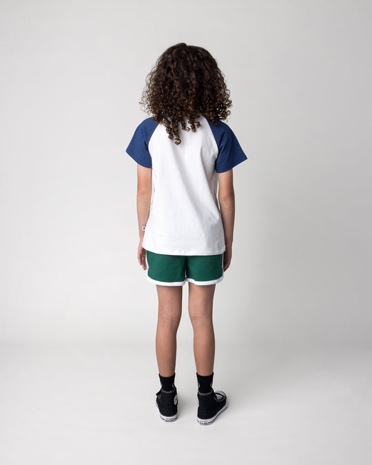 Kid wearing the Flower Penguin Tee in white, ink and yellow with the Sprint Short in kelly green and white, back view