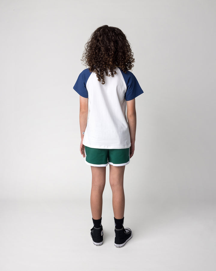 Kid wearing the Flower Penguin Tee in white, ink and yellow with the Sprint Short in kelly green and white, back view