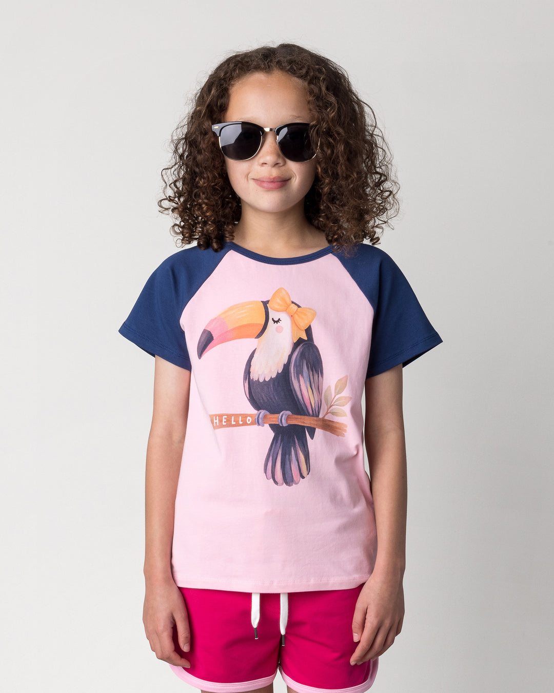 Close up of the Hello Toucan Tee in ballet and ink on a kid, front view