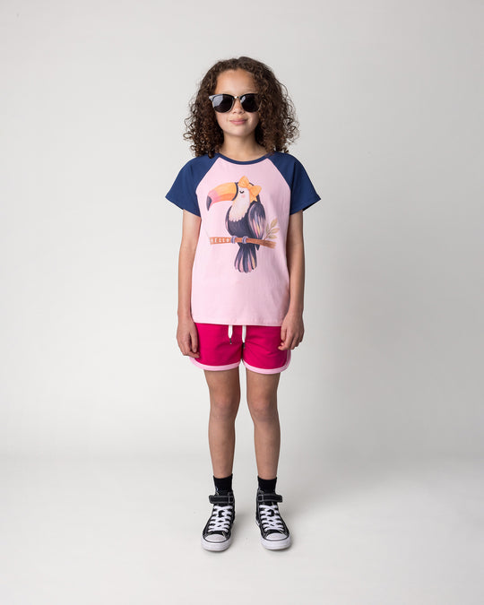 Kid wearing the Hello Toucan Tee in ballet and ink with the Sprint Short in crimson and pink, front view