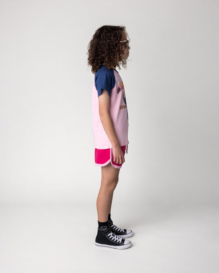 Kid wearing the Hello Toucan Tee in ballet and ink with the Sprint Short in crimson and pink, side view