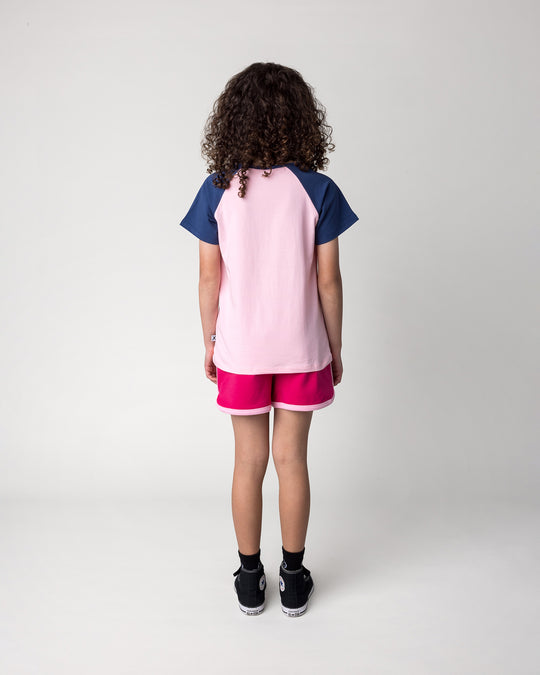 Kid wearing the Hello Toucan Tee in ballet and ink with the Sprint Short in crimson and pink, back view