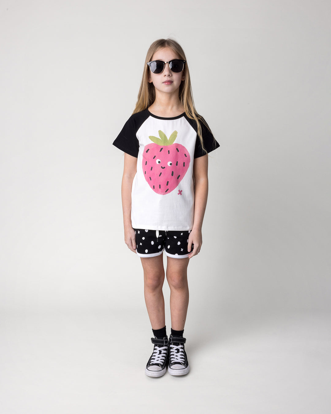 Kid wearing the Happy Strawberry Tee in white and black with the Spotty Short in black and white, front view
