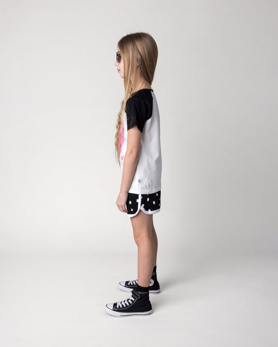 Kid wearing the Happy Strawberry Tee in white and black with the Spotty Short in black and white, side view