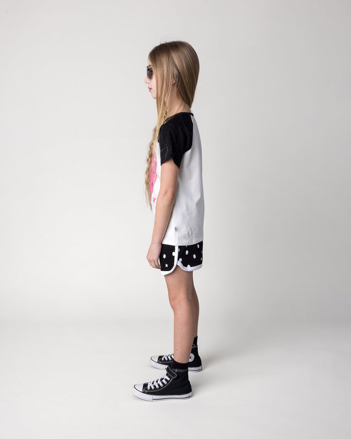 Kid wearing the Happy Strawberry Tee in white and black with the Spotty Short in black and white, side view