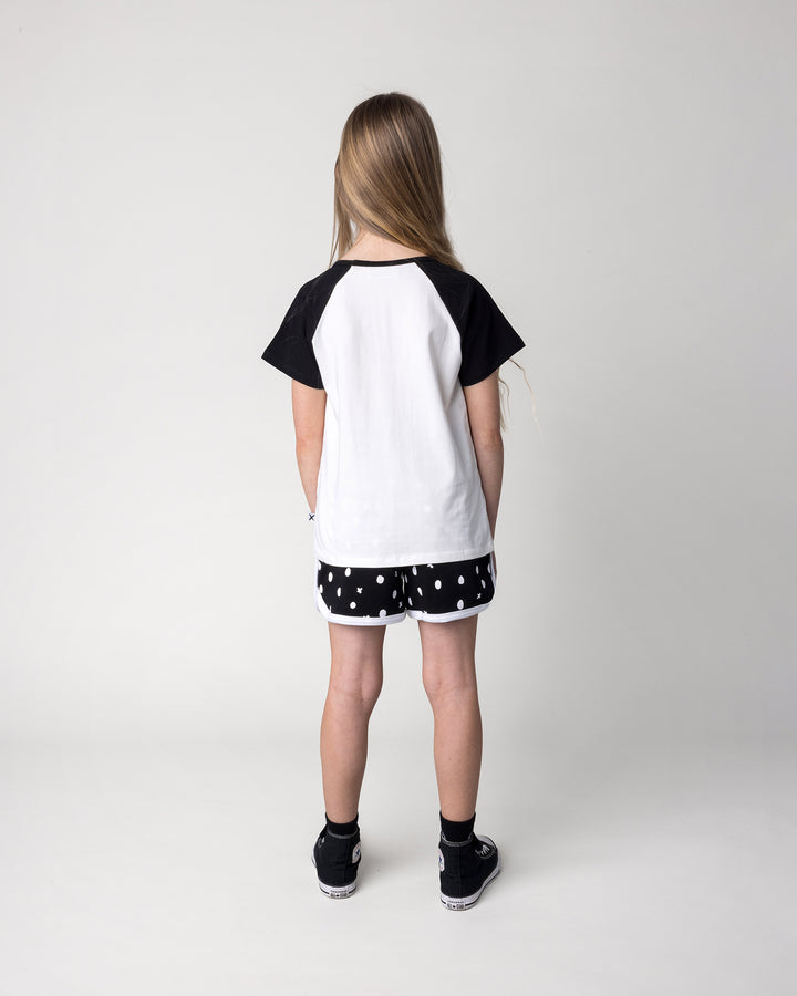 Kid wearing the Happy Strawberry Tee in white and black with the Spotty Short in black and white, back view