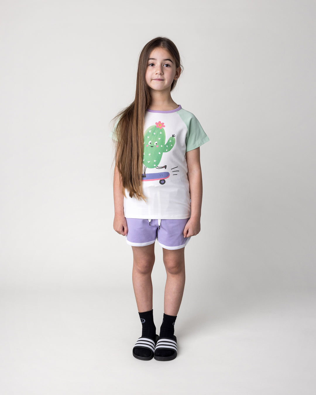 Kid wearing the Skate Cactus Tee in white and mint with the Sprint Short in lilac and white, front view